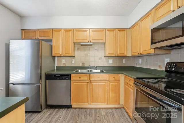 a kitchen with stainless steel appliances granite countertop a stove a sink and a refrigerator