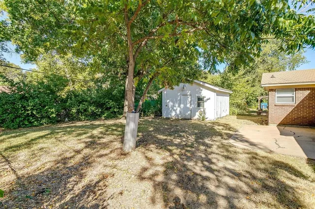 a backyard of a house with large trees and wooden fence