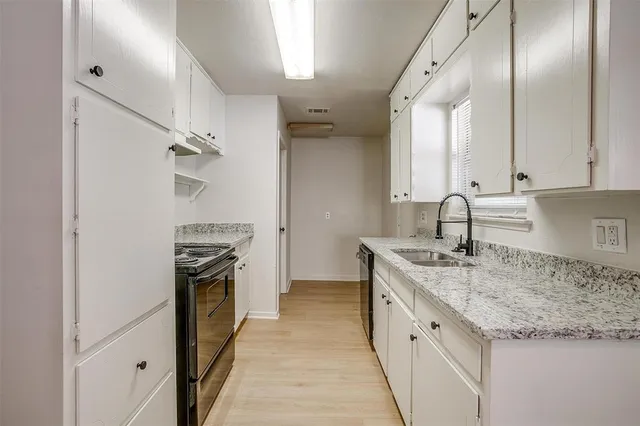 a kitchen with granite countertop a sink stove and refrigerator