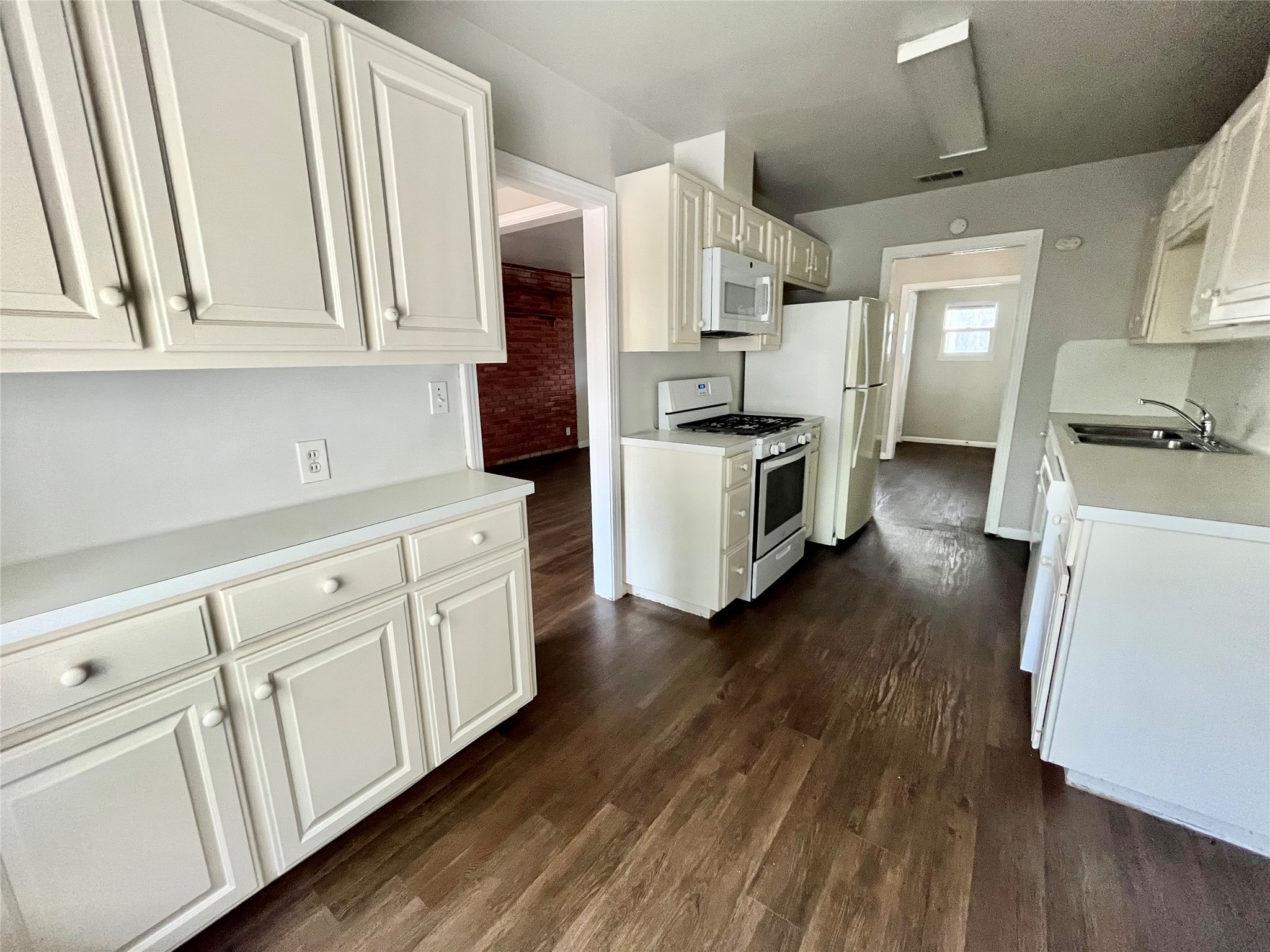 5101 Guadalupe Street, Unit A Austin, TX 78751 - Photo 8 of 28 Kitchen featuring light countertops, white appliances, dark wood-style flooring, and white cabinets