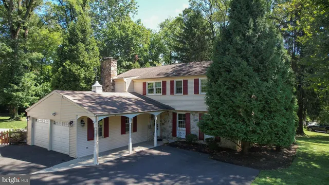 a view of a house with a yard and large trees