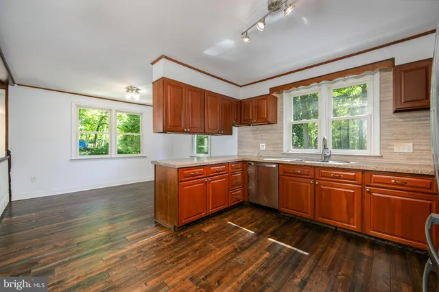 a kitchen with stainless steel appliances granite countertop a refrigerator a sink dishwasher a stove with wooden cabinets and floor