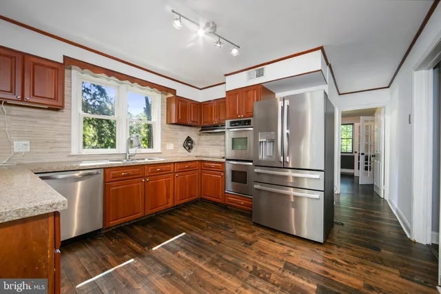 a kitchen with stainless steel appliances granite countertop a refrigerator and wooden cabinets