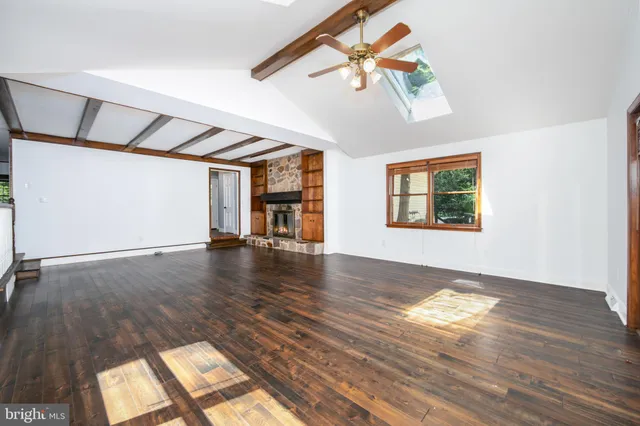 an empty room with wooden floor staircase and windows