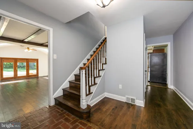 an empty room with wooden floor fireplace and chandelier