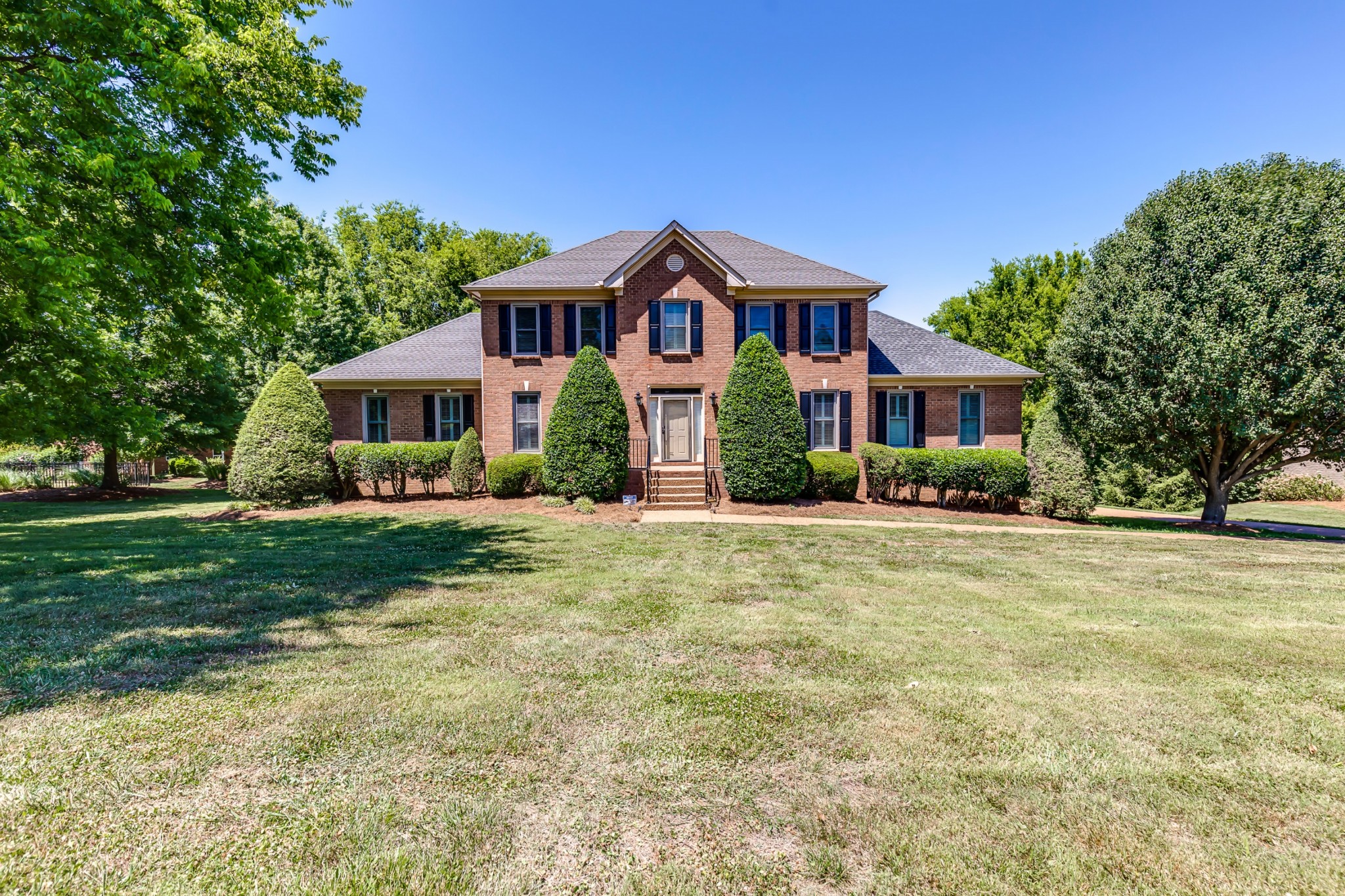 a front view of a house with yard and green space