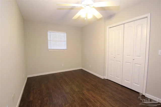 an empty room with wooden floor fan and windows