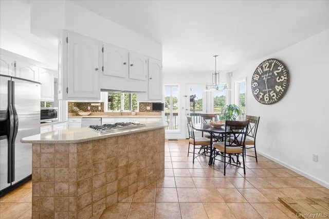a kitchen with stainless steel appliances granite countertop a sink a stove a dining table and chairs