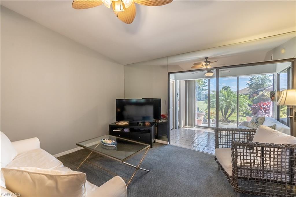 2048 Pine Isle Lane, Unit 2048 Naples, FL 34112 - Photo 11 of 50 a living room with furniture a flat screen tv and a floor to ceiling window