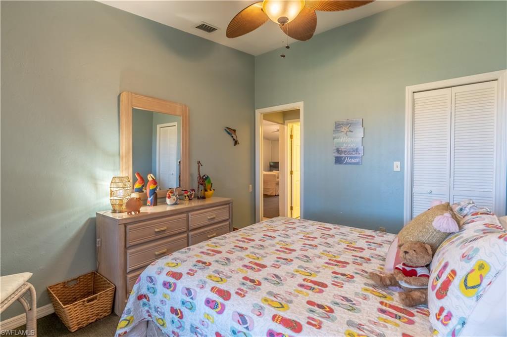 2048 Pine Isle Lane, Unit 2048 Naples, FL 34112 - Photo 15 of 50 a bedroom with a bed and a chandelier