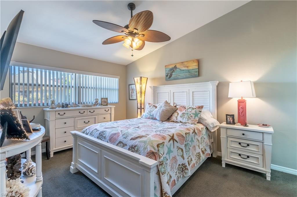 2048 Pine Isle Lane, Unit 2048 Naples, FL 34112 - Photo 18 of 50 a bedroom with a bed a chandelier and dresser