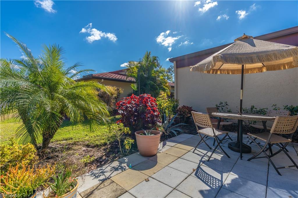 2048 Pine Isle Lane, Unit 2048 Naples, FL 34112 - Photo 29 of 50 a view of a patio with table and chairs under an umbrella
