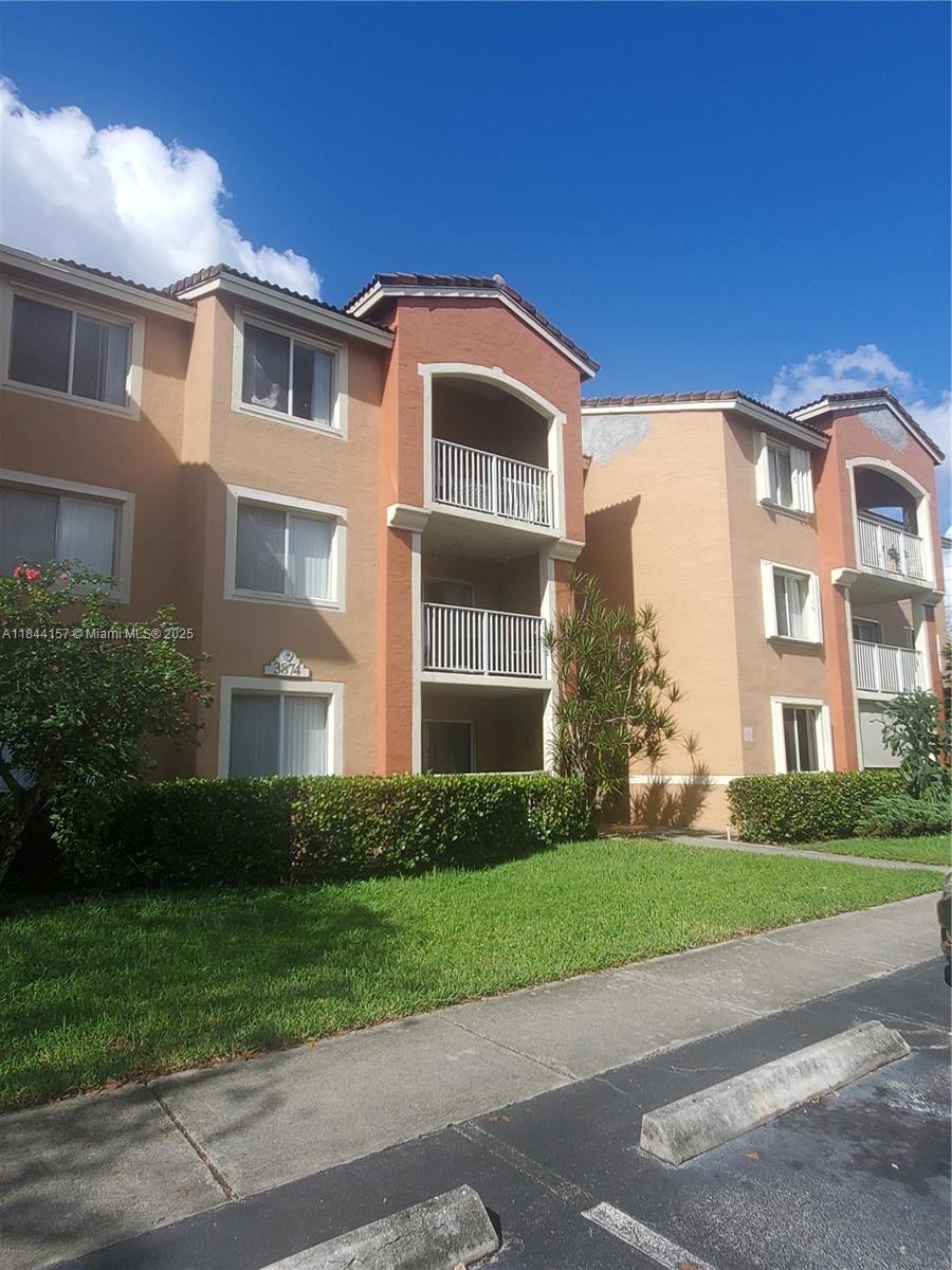 3874 Lyons Road, Unit 1126 Coconut Creek, FL 33073 - Photo 2 of 22 a front view of a residential apartment building with a yard