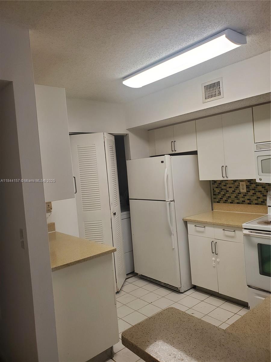 3874 Lyons Road, Unit 1126 Coconut Creek, FL 33073 - Photo 9 of 22 a utility room with cabinets washer and dryer
