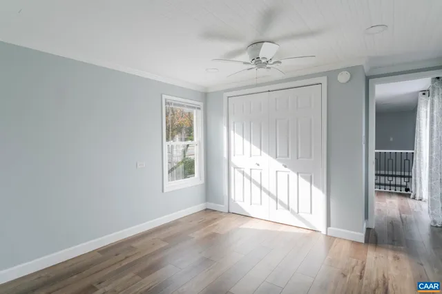 an empty room with wooden floor fan and windows