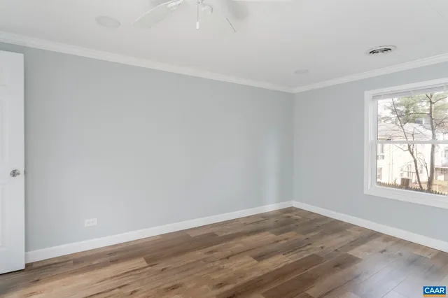 an empty room with wooden floor and windows