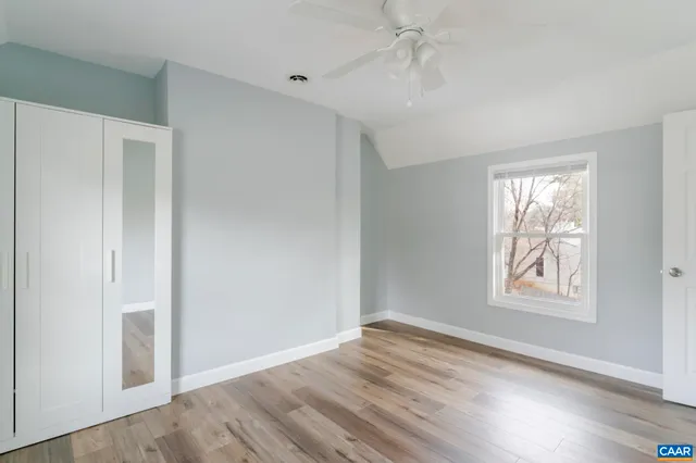 an empty room with wooden floor closet and windows