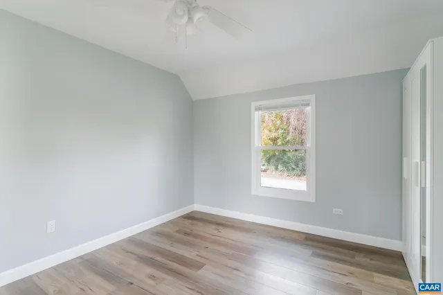 an empty room with wooden floor and window