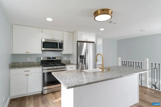 a kitchen with granite countertop a stove cabinets and wooden floor