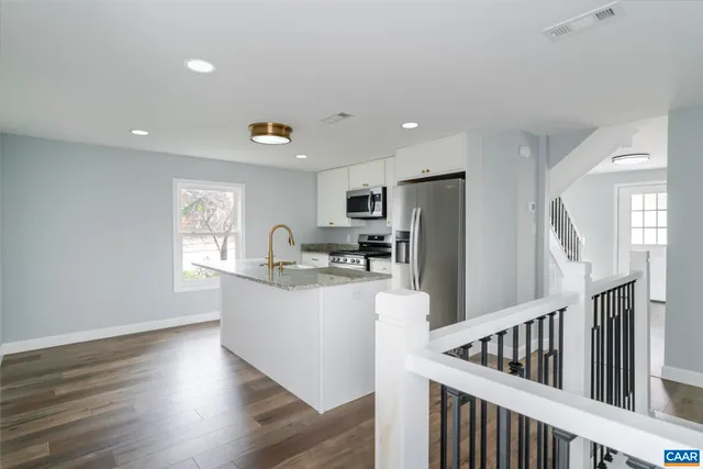 a living room with stainless steel appliances granite countertop a refrigerator a sink a stove a dining table and chairs