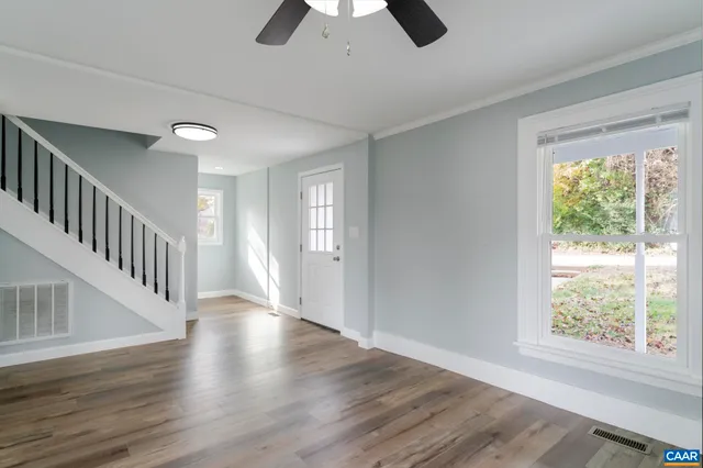 a view of an empty room with window and wooden floor