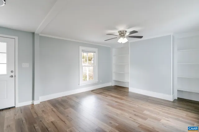 an empty room with wooden floor and windows