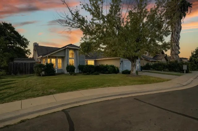 a view of a house next to a yard with big trees