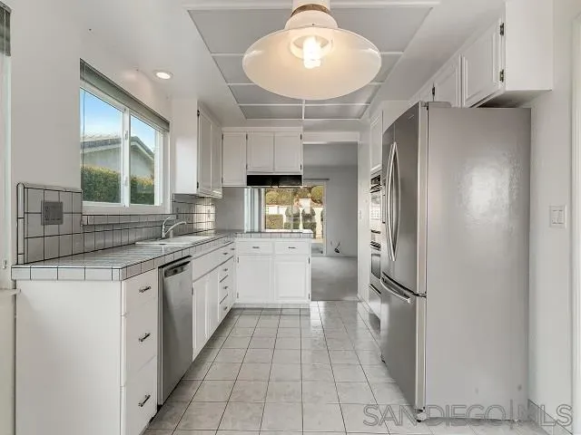 a large kitchen with stainless steel appliances a refrigerator and a sink