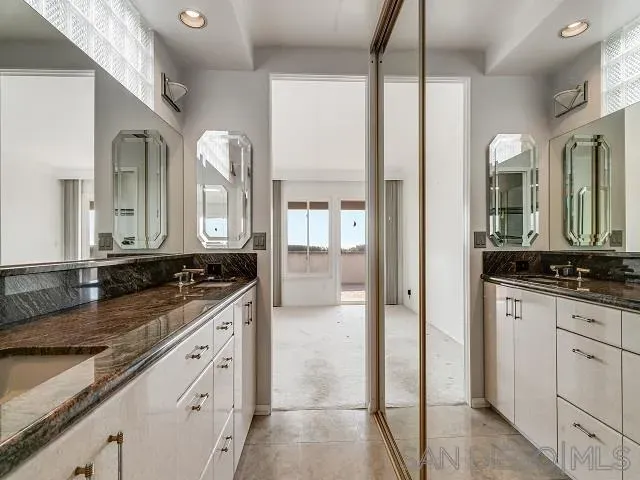 a bathroom with a granite countertop sink two mirror and a shower