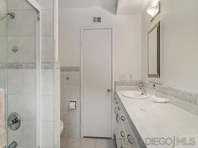 a bathroom with a granite countertop sink two mirror and shower