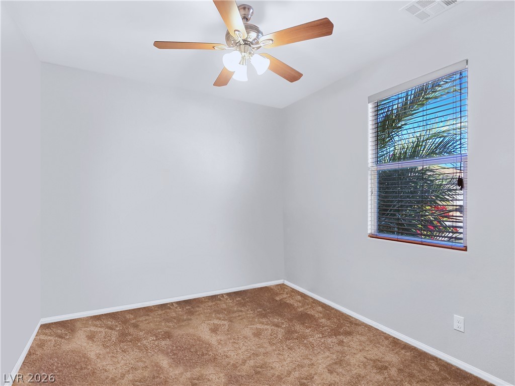 2485 Morrow Ridge Place Laughlin, NV 89029 - Photo 18 of 38 A well-lit room offers a textured carpet and a window looking out onto greenery.