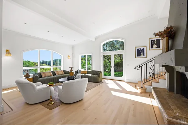 a living room with furniture large windows and wooden floor