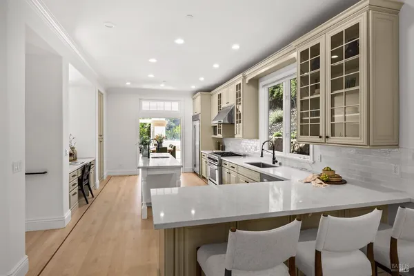 a kitchen with stove a sink dishwasher and white cabinets with wooden floor