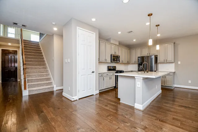 a kitchen with stainless steel appliances granite countertop a sink a stove a refrigerator and island with wooden floor