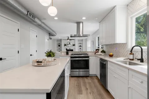 a kitchen with granite countertop a sink and a white wooden cabinets
