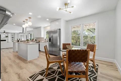 a dining room filled chandelier and wooden floor