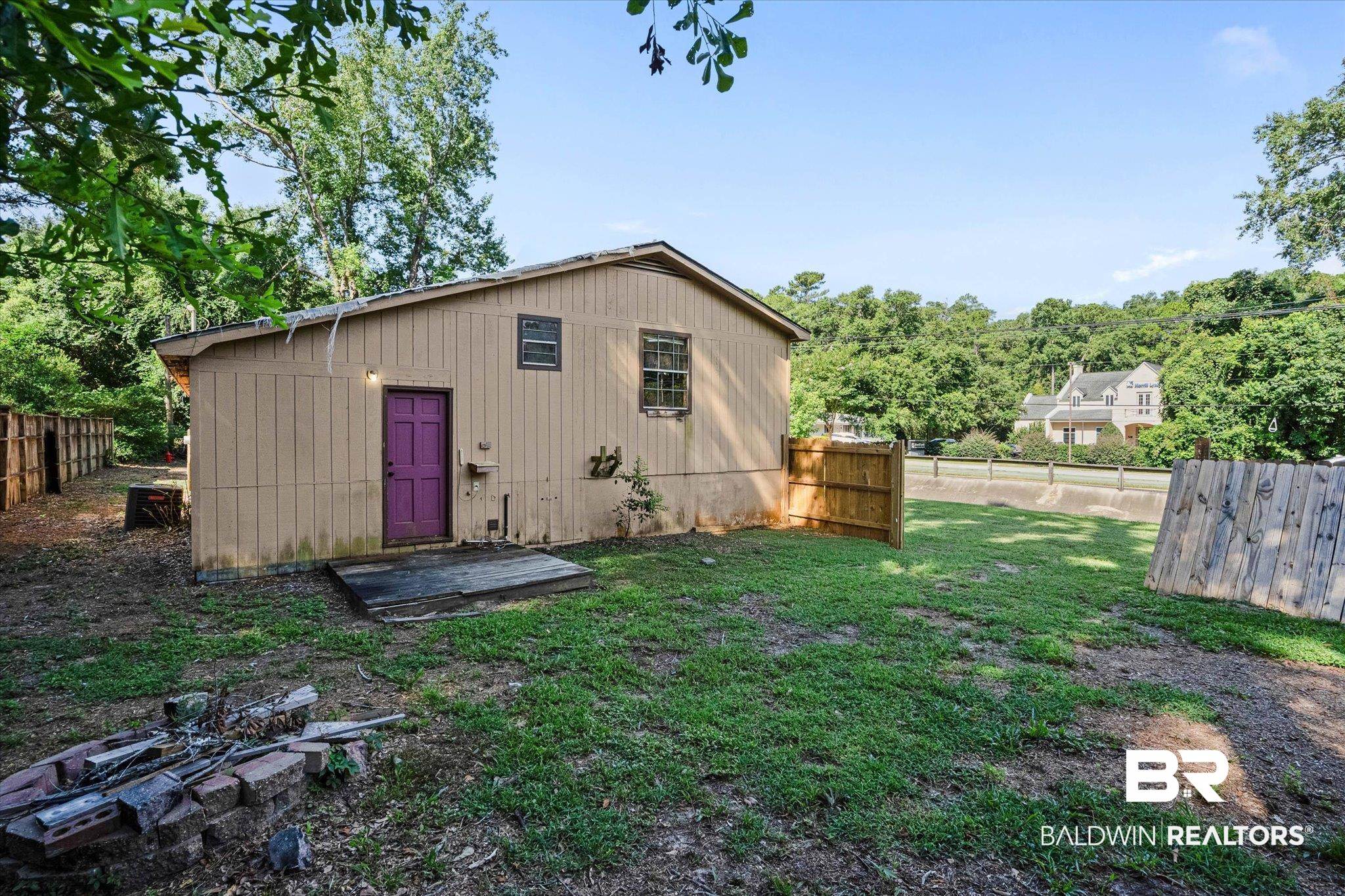 401 Frederick Avenue Fairhope, AL 36532 - Photo 20 of 36 Backyard featuring a wood-panel exterior, a purple door, and a partially fenced perimeter