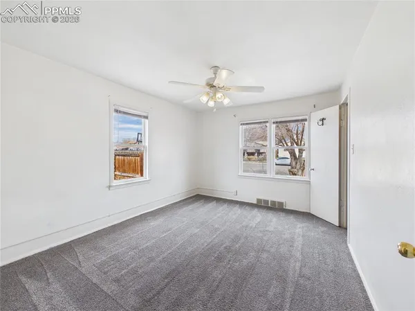 an empty room with windows and ceiling fan
