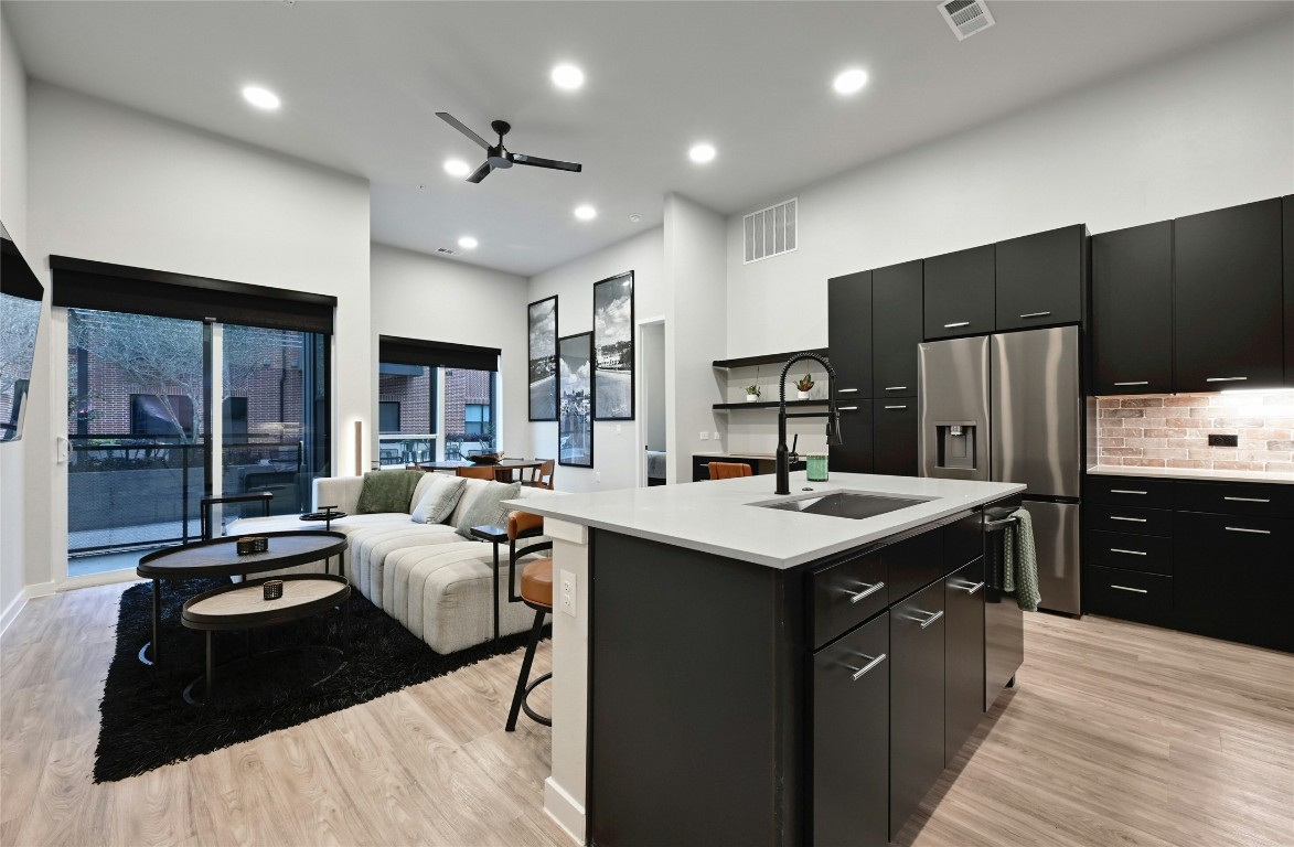 4510 Terry-O Lane, Unit 138 Austin, TX 78745 - Photo 1 of 40 a large kitchen with stainless steel appliances kitchen island granite countertop a refrigerator a sink dishwasher a stove and a dining table with wooden floor