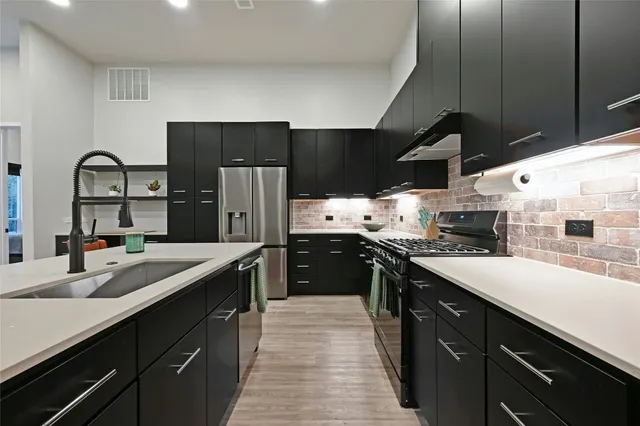 a kitchen with stainless steel appliances a sink stove and refrigerator