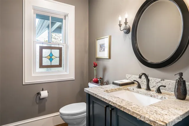 a bathroom with a granite countertop toilet a sink and a mirror