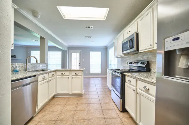 a large kitchen with stainless steel appliances granite countertop a stove and a sink