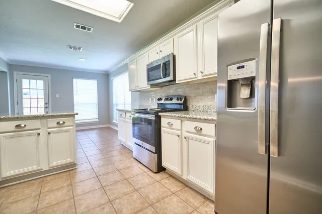 a kitchen with stainless steel appliances granite countertop a refrigerator and a stove top oven