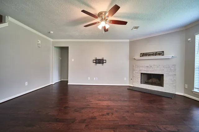 a view of an empty room with wooden floor a fireplace and a window