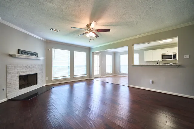 a view of an empty room with wooden floor and a fireplace