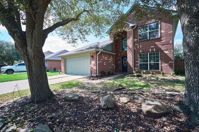 a view of a house with a yard and large tree
