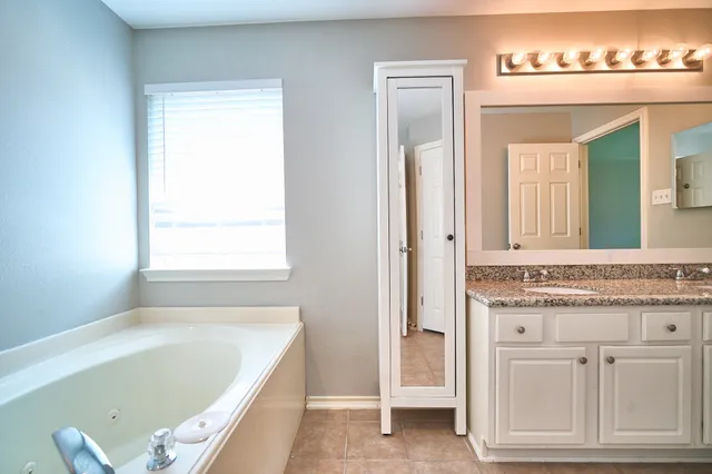 a bathroom with a tub a sink and a window