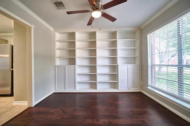 a view of an empty room with a window and wooden floor