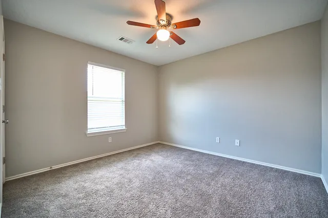an empty room with windows and fan