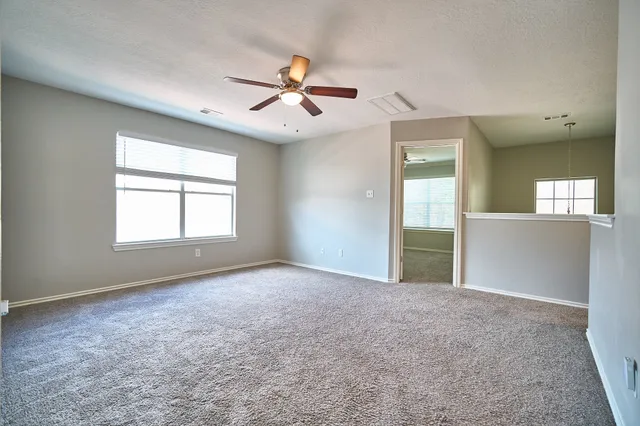 an empty room with windows and fan chandelier